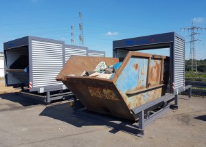 Geöffnete Containerüberdachung in dem eine Mulde mit Restmüll gelagert wird
